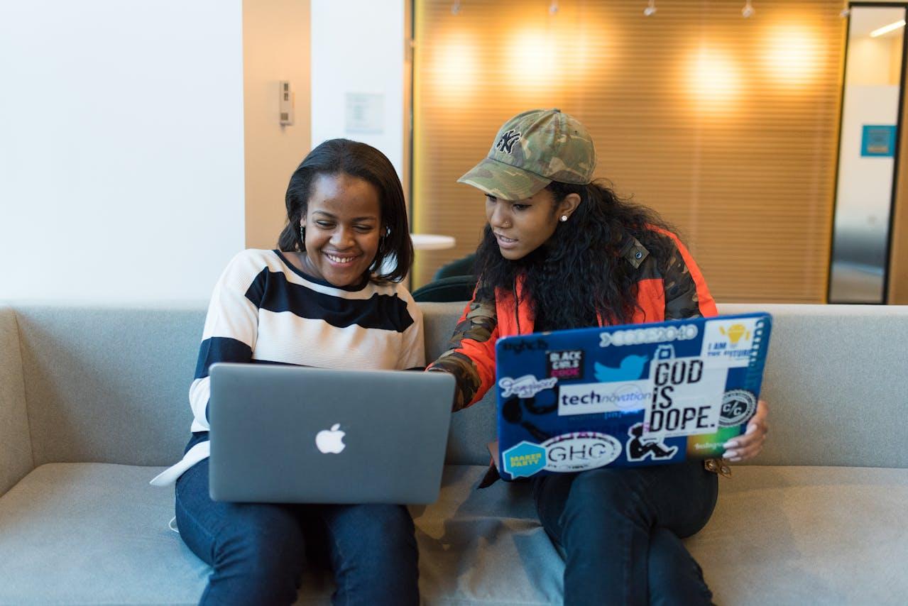 Smiling woman with wireless headphones watching entertainment show laptop while sitting desk african american freelancer looking funny social media content portable computer