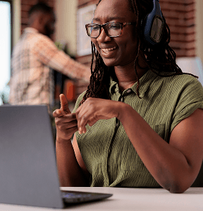 Smiling woman with wireless headphones watching entertainment show laptop while sitting desk african american freelancer looking funny social media content portable computer
